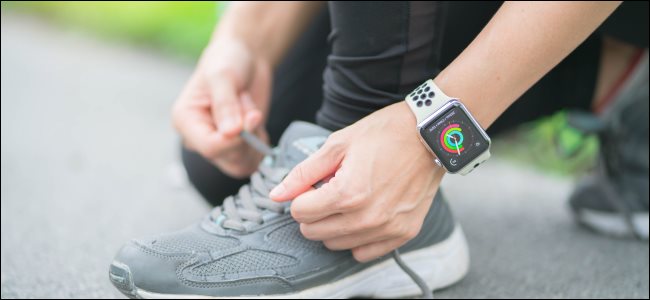 Una mujer atándose los cordones de sus zapatos mientras usa un Apple Watch.