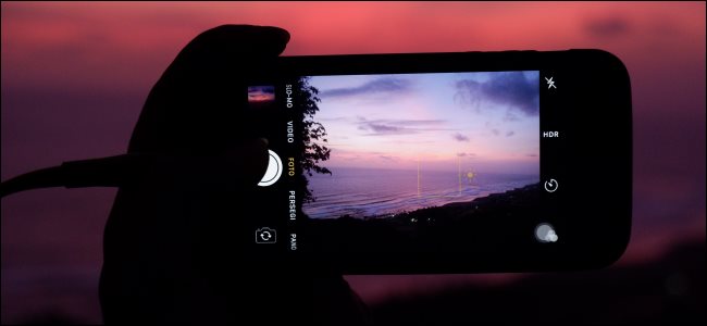 Alguien que toma una fotografía de una puesta de sol al anochecer con un iPhone.